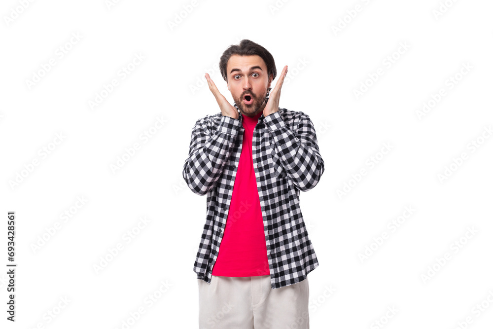 young surprised bearded brunette man in a shirt on a white background with copy space young surprised bearded brunette man in a shirt on a white background with copy space