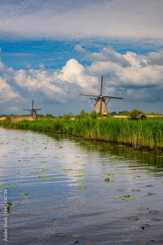 View of traditional windmills and canals in Kinderdijk Village in the Netherlands, South Holland. Famous tourist attraction in Holland. Beautiful Dutch landscape with dramatic sky. 