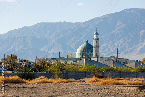 Al Amin mosque in Balykchy, Kyrgyzstan in front of mountains at sunny autumn day. photo