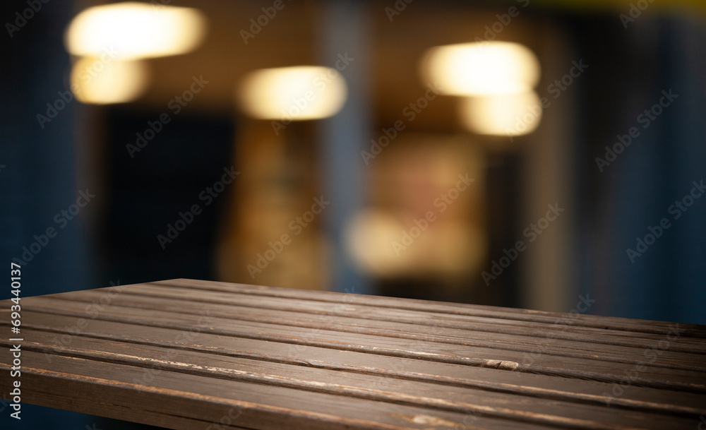 Empty wooden table top on blur light golden bokeh of cafe restaurant, bar in a dark background. Empty wooden table top on blur light golden bokeh of cafe restaurant, bar in a dark background.