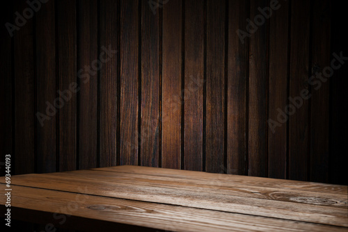 image of a wooden table on an abstract dark background with light in the center © Egor