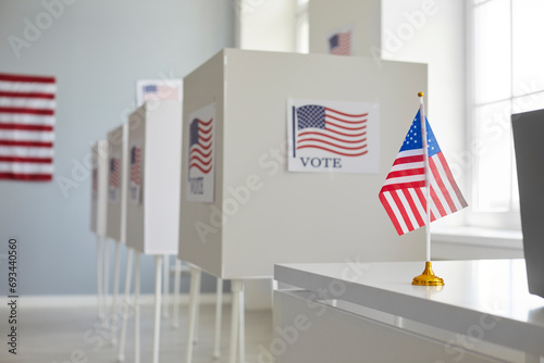 Empty polling station with row of white voting booths decorated with American flag at vote center. Presidential American elections in the United States. Democracy and election day concept. photo