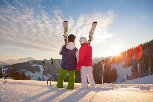 Skiing couple standing in deep snow powder, enjoy a perfect sunset in the Austrian Alps. photo