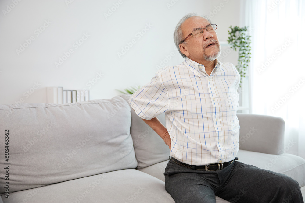 senior man suffering from back pain on sofa senior man suffering from back pain on sofa