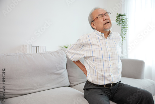 senior man suffering from back pain on sofa © offsuperphoto