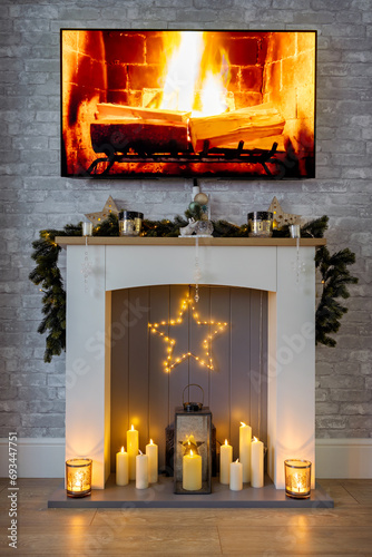 Fire surround, dressed for Christmas with garland, star and candles and a fire on the tv