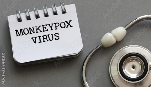 MONKEYPOX VIRUS words written with stethoscope on grey background. Monkeypox also known as the Moneypox virus. photo