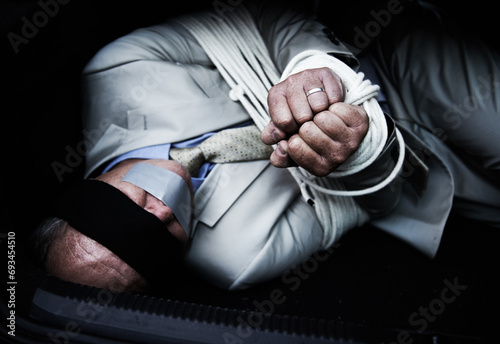 Man in trunk of car, kidnap and rope with danger, criminal violence and fear for human trafficking crisis. Crime, mafia problem and scared person tied in back of vehicle with risk, terror and robbery © Jeff Bergen/peopleimages.com