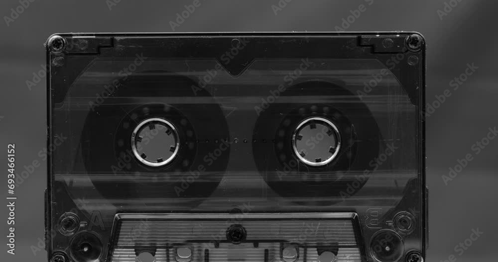 Audio cassette tape in use, rotation of rolls of film, white background