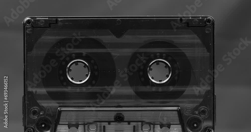 Audio cassette tape in use, rotation of rolls of film, white background photo
