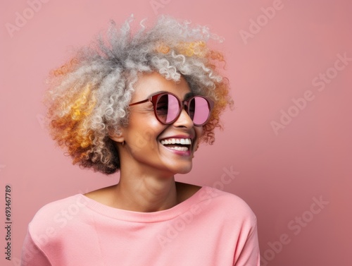 African american senior woman with afro hairstyle and sunglasses isolated on pink background. Close-up of an aged model smiling. Copy space for text