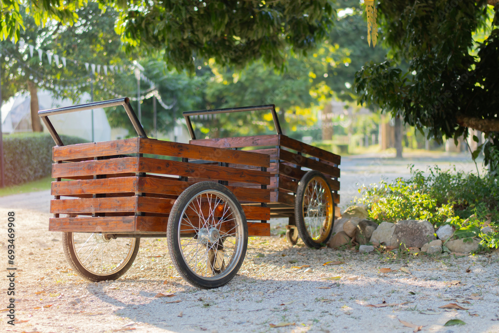 Vintage wooden carts with empty stand on green garden under big tree