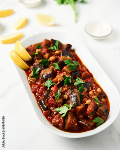 Maghmour or Lebanese moussaka. Dish made from baked or fried eggplant with spices, chickpeas and tomato sauce. Eggplants are stewed in tomato sauce photo