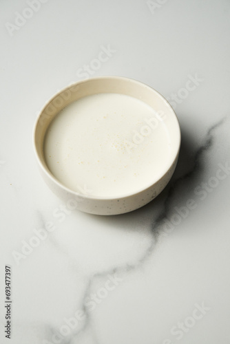 Heavy cream in the white bowl on white marble background