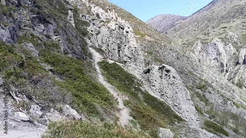 A short and narrow path rises uphill to meet tall stone statues on a sunny spring day. Stone mushrooms, Altai, Siberia, Russia. photo