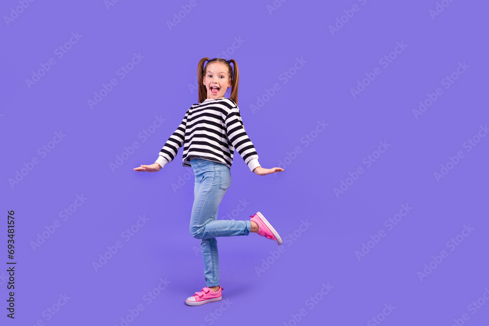 Full length photo of carefree excited little child dressed striped pullover having fun empty space isolated purple color background