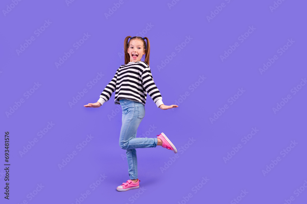 Fototapeta premium Full length photo of carefree excited little child dressed striped pullover having fun empty space isolated purple color background