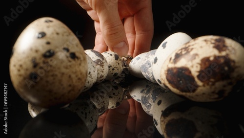 I'm picking up quail eggs one by one from a black table, close-up.