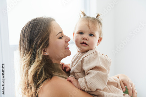 young beautiful mother with a baby girl having great time at home