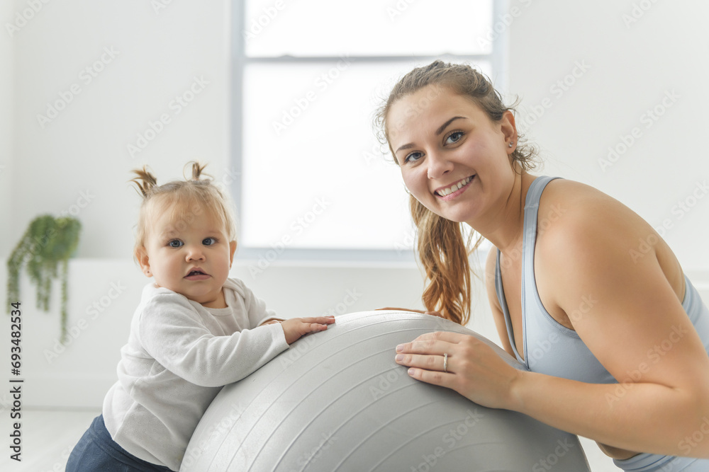 Fototapeta premium Sport Activities With Baby. Young Mom Exercising With Her Infant Son At Home