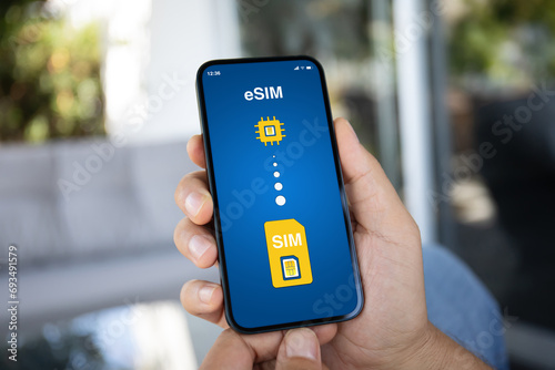 Man hand hold phone with Sim card replacement on eSim photo