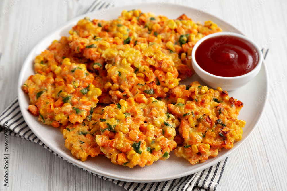Homemade Carrot Corn Fritters with Ketchup on a Plate, side view. Homemade Carrot Corn Fritters with Ketchup on a Plate, side view.
