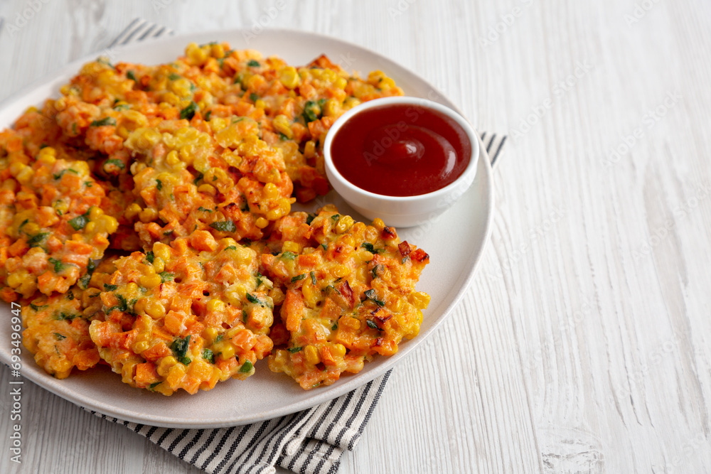 Homemade Carrot Corn Fritters with Ketchup on a Plate, side view. Copy space. Homemade Carrot Corn Fritters with Ketchup on a Plate, side view. Copy space.