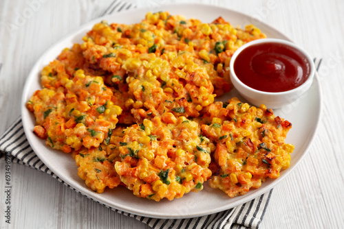 Homemade Carrot Corn Fritters with Ketchup on a Plate, side view.
