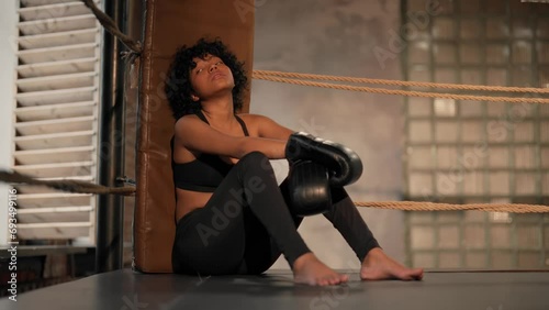 Wallpaper Mural Tired curly american sportswoman boxer rests after high training sits on ring in gym. She closes her eyes and relaxes. Sport, active training workout, professional girl fighter after workout. Torontodigital.ca