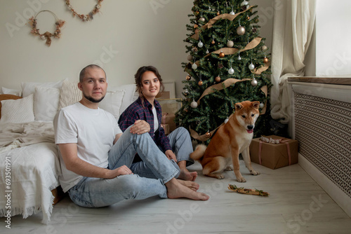 Happy beautiful couple with shiba inu dog at christmas at home © Stanislava