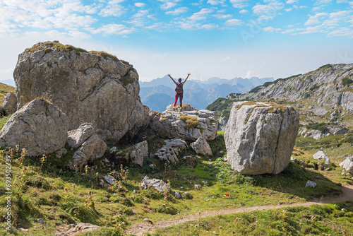 Fotografie young woman hiker with outstretched arms, standing between big rocks at Rofan al