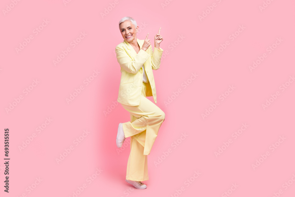 Full body photo of positive person dressed yellow jacket trousers dancing directing at offer empty space isolated on pink color background Full body photo of positive person dressed yellow jacket trousers dancing directing at offer empty space isolated on pink color background