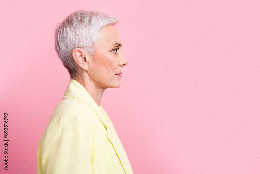Side profile photo of confident serious mature woman white short haircut looking empty space ad isolated over pink color background Side profile photo of confident serious mature woman white short haircut looking empty space ad isolated over pink color background