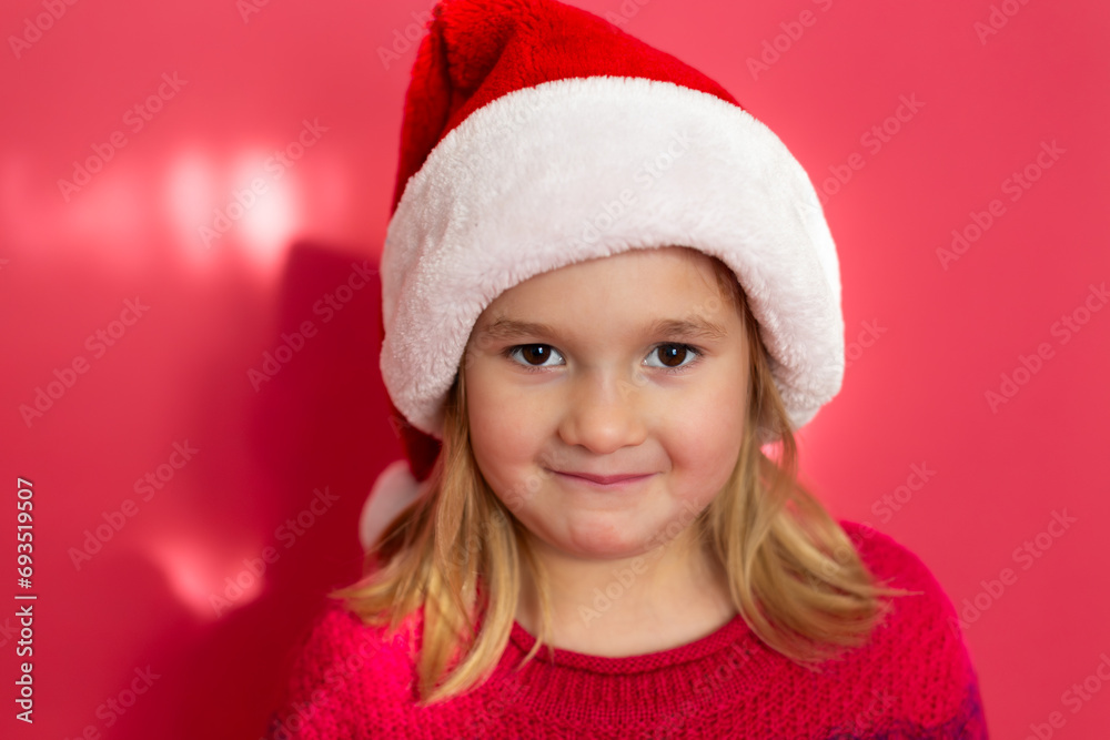 Selective focus closeup of cute smiling little girl in red sweater and Santa hat Selective focus closeup of cute smiling little girl in red sweater and Santa hat