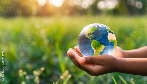 hands of a african american child holding crystal glowing globe planet earth at a sunny green meadow background copyspace taking care ecology sustainable nature conversation concept ai generated photo