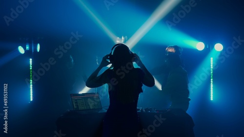Female DJ Leading the Party at Nightclub with Crowd in Silhouette