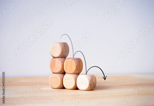 Black down arrows jumping down on wood blocks stacked, decrease business graph step on white background. Financial crisis, bankruptcy, loss investment economic recession sales risk concepts. photo