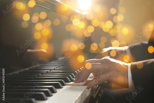 Christmas and New Year music. Man playing piano, closeup. Bokeh effect photo