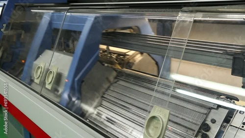 View of working knitting machine in workshop. A row of industrial textil flat knitting machines in a knitwear factory. Manufacture of knitwear, modern computerized flat Knitting Machine