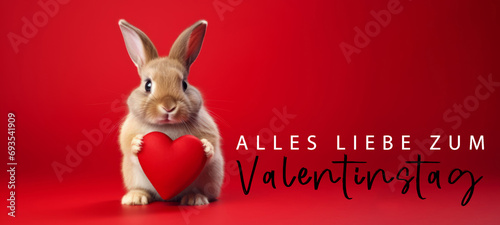 Alles Liebe zum Valentinstag, Grußkarte mit deutschem Text - Niedliche Hase Kaninchen hält rotes Herz , isoliert auf rotem Hintergrund © Corri Seizinger