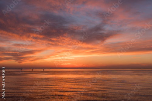 遠くに桟橋の見える、赤く染まった夕暮れの海と美しい空