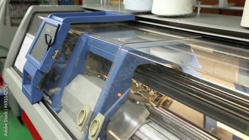 View of working knitting machine in workshop. A row of industrial textil flat knitting machines in a knitwear factory. Manufacture of knitwear, modern computerized flat Knitting Machine