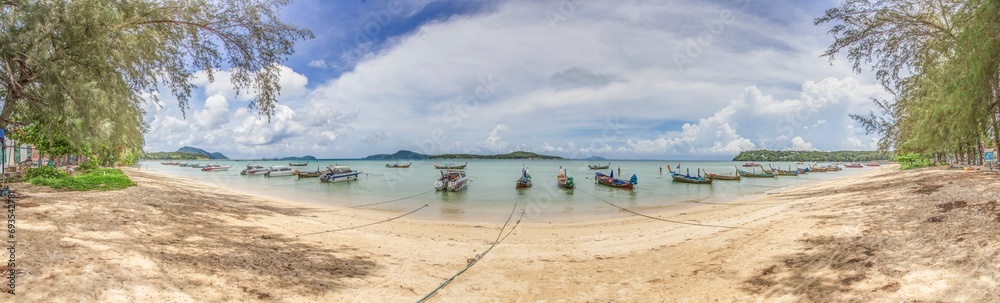 Panoramic picture of a tropical beach on the Thai island of Phuket with traditional longtail boats