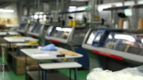 Blurred background view of working knitting machine in workshop. A row of industrial textil flat knitting machines in a knitwear factory. Manufacture of knitwear, modern computerized flat Knitting