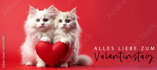 Alles Liebe zum Valentinstag, Grußkarte mit deutschem Text - Niedliches Katzen Päärchen hält rotes Herz , isoliert auf rotem Hintergrund © Corri Seizinger