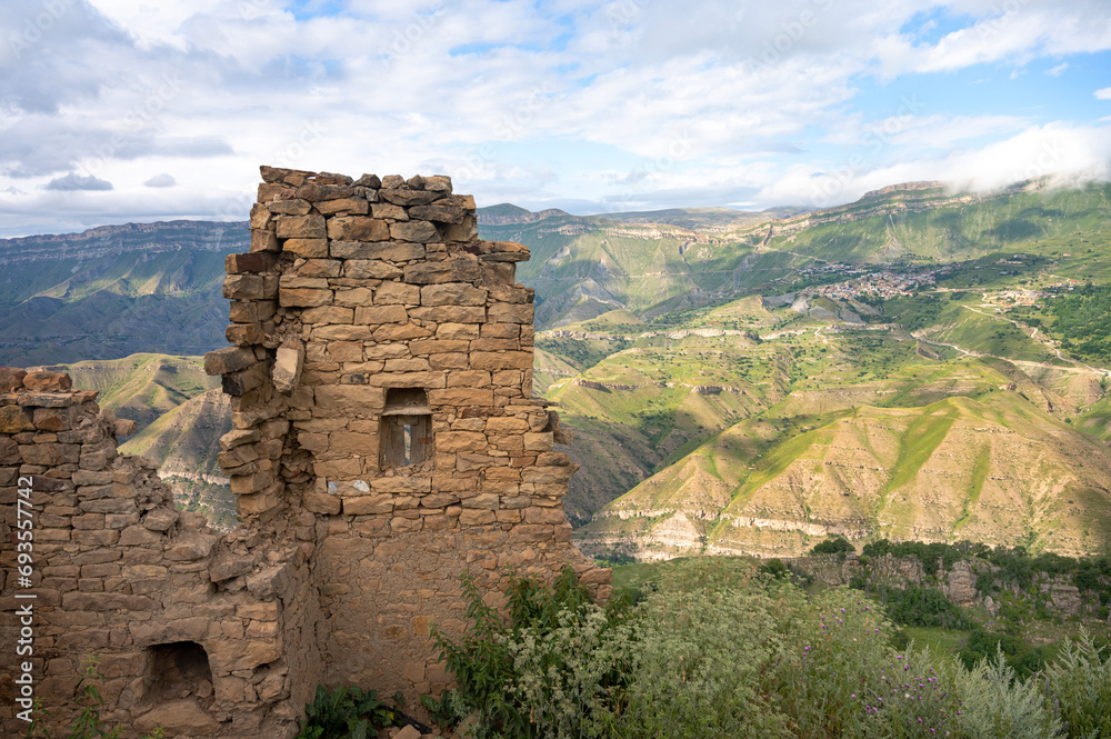 Landscape of the old ruins of an ancient city in an abandoned mountain village, located on a steep hillside among a mountainous landscape. Gamsutl, Dagestan, Russia.
