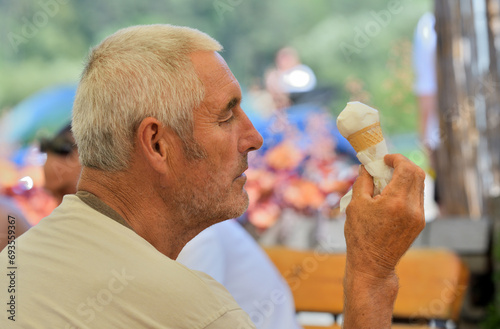 Obraz na płótnie Close-up of an elderly man's mouth licking a sweet ice cream with his tongue w salonie