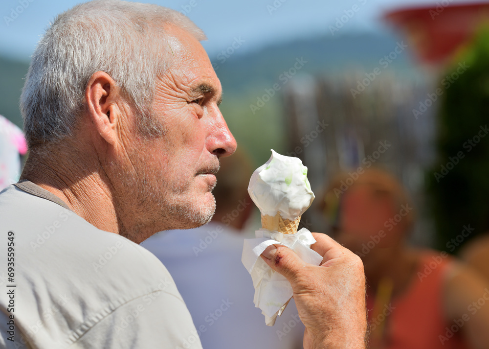 Close-up of an elderly man's mouth licking a sweet ice cream with his tongue