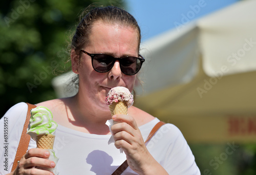 Obraz na płótnie Close-up of a woman's mouth licking sweet ice cream with her tongue w salonie