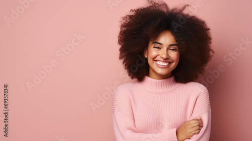 A woman with dark skin and curly hair is standing with crossed fingers and waiting for important news. she is wearing a casual jumper and her body language demonstrates a sweet desire, photo